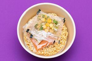 Opened Package with Uncooked Instant Noodles on Violet Background. Raw Pasta. Dry Asian Fast Food. Quick Lunch photo
