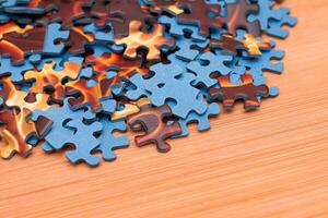 Colorful Pieces of a Mixed Jigsaw Puzzle Lie on the Wooden Table - Strategy and Solving Problem Concept photo