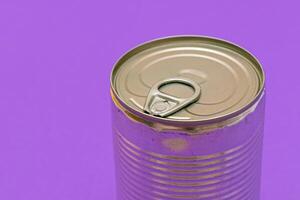 Unopened Tin Can with Blank Edge on Violet Background. Canned Food. Aluminum Can for Safe and Long Term Storage of Food. Steel Sealed Food Storage Container photo