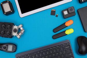 Top View of Photographer's, Videographer's or Blogger's Workplace. Digital Gadgets Lying on Blue Table - Flat Lay photo