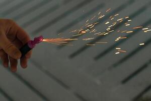 Burning Firecracker with Sparks. Guy Holding a Petard in a Hand. Loud and Dangerous New Year's Entertainment. Hooliganism with Pyrotechnics. Noise of Firecrackers in Public Places photo