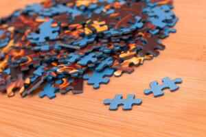 Colorful Pieces of a Mixed Jigsaw Puzzle Lie on the Wooden Table - Strategy and Solving Problem Concept photo
