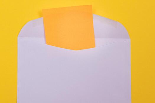 Violet Envelope with Blank Orange Sheet of Paper Inside, Lying on Yellow Background - Mock Up with Copy Space. Receiving Mail or Notice, Sending Postcard - Top View, Flat Lay photo