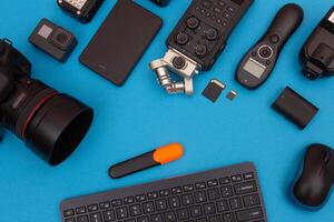 Top View of Photographer's, Videographer's or Blogger's Workplace. Digital Gadgets Lying on Blue Table - Flat Lay photo