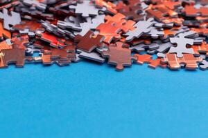 Mixed Pieces of a Colorful Jigsaw Puzzle Lie on the Blue Background With Copy Space - Strategy and Solving Problem Concept photo