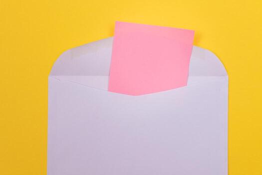 Violet Envelope with Blank Pink Sheet of Paper Inside, Lying on Yellow Background - Mock Up with Copy Space. Receiving Mail or Notice, Sending Postcard - Top View, Flat Lay photo