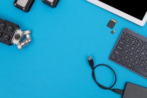 Top View of Photographer's, Videographer's or Blogger's Workplace. Digital Gadgets Lying on Blue Table - Flat Lay photo
