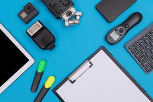 Top View of Photographer's, Videographer's or Blogger's Workplace. Digital Gadgets Lying on Blue Table - Flat Lay photo
