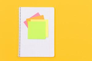 A Notepad with Sticky Notes Lying on Yellow Table - Blank Template. Top View, Flat Lay photo
