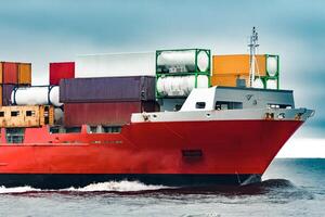 Red cargo container ship's bow in cloudy day photo