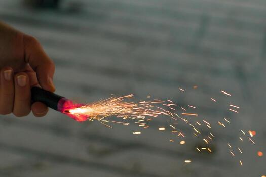 Burning Firecracker with Sparks. Guy Holding a Petard in a Hand. Loud and Dangerous New Year's Entertainment. Hooliganism with Pyrotechnics. Noise of Firecrackers in Public Places photo