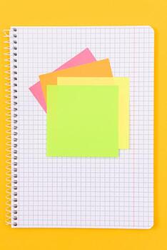 A Notepad with Sticky Notes Lying on Yellow Table - Blank Template. Top View, Flat Lay photo