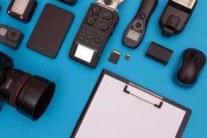 Top View of Photographer's, Videographer's or Blogger's Workplace. Digital Gadgets Lying on Blue Table - Flat Lay photo