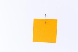 Mockup of a Blank Orange Memo Paper with Copy Space Hanging on a Fishing Hook Against the White Background. Reminder or To Do List. Sticky Note Template photo