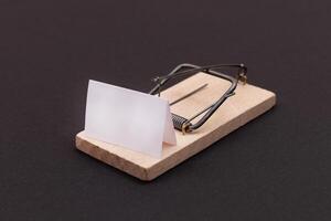 Blank White Sheet of Paper in Wooden Mousetrap - Template. Small Memo Paper in Mouse Trap on Black Background photo