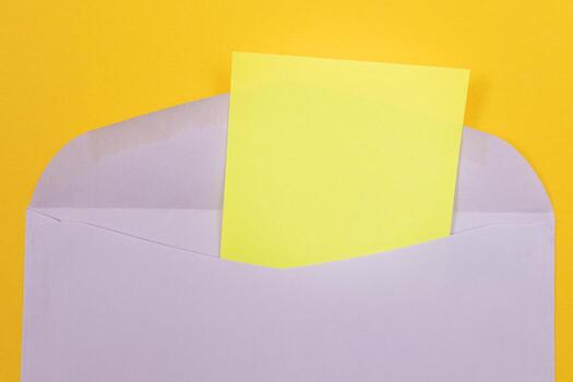 Violet Envelope with Blank Yellow Sheet of Paper Inside, Lying on Yellow Background - Mock Up with Copy Space. Receiving Mail or Notice, Sending Postcard - Top View, Flat Lay photo