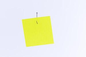 Mockup of a Blank Yellow Memo Paper with Copy Space Hanging on a Fishing Hook Against the White Background. Reminder or To Do List. Sticky Note Template photo