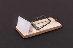 Blank White Sheet of Paper in Wooden Mousetrap - Template. Small Memo Paper in Mouse Trap on Black Background photo