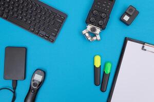 Top View of Photographer's, Videographer's or Blogger's Workplace. Digital Gadgets Lying on Blue Table - Flat Lay photo