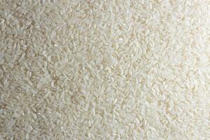 Dry Uncooked White Rice Background - Top View, Flat Lay. Scattered Raw Long Grain Rice. Asian Cuisine and Culture. Healthy Eating Ingredients. Diet Food photo