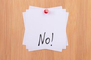 NO - White Sticky Notes with Written Word NO, Pinned to the Wooden Message Board. To Do List Reminder in the Office. Memo Note at Work photo