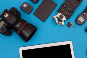 Top View of Photographer's, Videographer's or Blogger's Workplace. Digital Gadgets Lying on Blue Table - Flat Lay photo