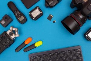 Top View of Photographer's, Videographer's or Blogger's Workplace. Digital Gadgets Lying on Blue Table - Flat Lay photo