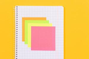 A Notepad with Sticky Notes Lying on Yellow Table - Blank Template. Top View, Flat Lay photo