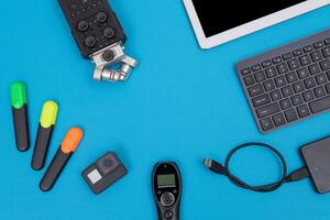 Top View of Photographer's, Videographer's or Blogger's Workplace. Digital Gadgets Lying on Blue Table - Flat Lay photo