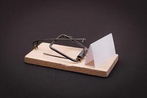 Blank White Sheet of Paper in Wooden Mousetrap - Template. Small Memo Paper in Mouse Trap on Black Background photo