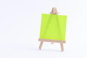 Wooden Easel Miniature with Blank Colored Square Canvas or Memo Paper - Mockup. Mini Wooden Stand with Clean Artboard on White Background, Copy Space photo