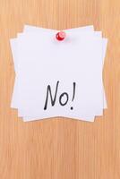 NO - White Sticky Notes with Written Word NO, Pinned to the Wooden Message Board. To Do List Reminder in the Office. Memo Note at Work photo