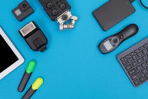 Top View of Photographer's, Videographer's or Blogger's Workplace. Digital Gadgets Lying on Blue Table - Flat Lay photo