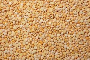 Uncooked Polished Split Peas Background. A Culinary Canvas of Dry Yellow Peas, Creating a Lively and Textured Background for Gourmet Cooking. Scattered Raw Polished Peas. Healthy Eating Ingredients photo