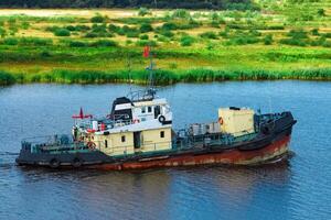 Old tug ship moving to the cargo terminal. Industrial service photo
