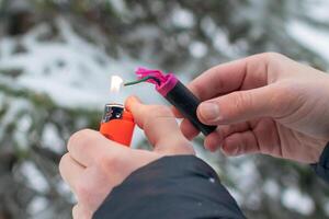 Guy Sets Fire to the Flash Noise Firecracker Outdoors in Winter at Daytime. Loud and Dangerous New Year's Entertainment. Hooliganism with Pyrotechnics. Noise of Petards in Public Places photo