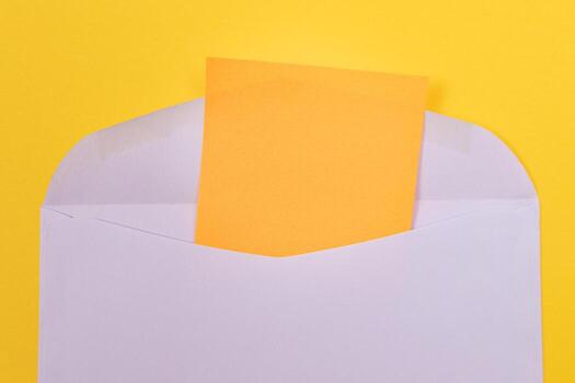 Violet Envelope with Blank Orange Sheet of Paper Inside, Lying on Yellow Background - Mock Up with Copy Space. Receiving Mail or Notice, Sending Postcard - Top View, Flat Lay photo