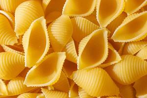 Uncooked Conchiglie Pasta. A Culinary Canvas of Conchiglie Macaroni, Creating a Lively and Textured Background for Gourmet Cooking. Dry Pasta. Raw Macaroni - Top View, Flat Lay photo
