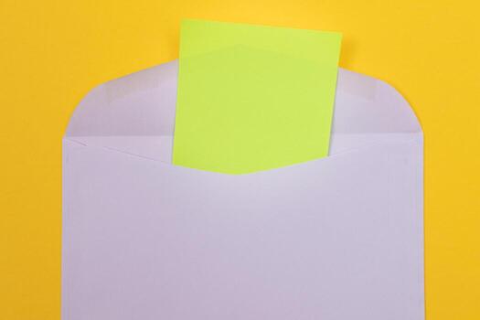 Violet Envelope with Blank Green Sheet of Paper Inside, Lying on Yellow Background - Mock Up with Copy Space. Receiving Mail or Notice, Sending Postcard - Top View, Flat Lay photo