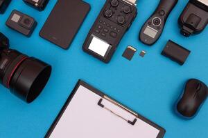 Top View of Photographer's, Videographer's or Blogger's Workplace. Digital Gadgets Lying on Blue Table - Flat Lay photo