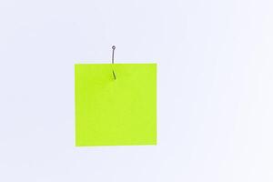 Mockup of a Blank Green Memo Paper with Copy Space Hanging on a Fishing Hook Against the White Background. Reminder or To Do List. Sticky Note Template photo