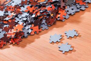 Colorful Pieces of a Mixed Jigsaw Puzzle Lie on the Wooden Table - Strategy and Solving Problem Concept photo