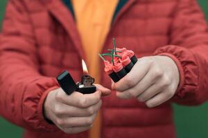 Man in Red Jacked Lighting Up Several Firecrackers in his Hand Using Gasoline Lighter. Guy Getting Ready for New Year Fun with Fireworks or Pyrotechnic Products photo