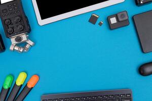 Top View of Photographer's, Videographer's or Blogger's Workplace. Digital Gadgets Lying on Blue Table - Flat Lay photo