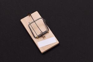 Blank White Sheet of Paper in Wooden Mousetrap - Template. Small Memo Paper in Mouse Trap on Black Background photo