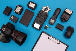 Top View of Photographer's, Videographer's or Blogger's Workplace. Digital Gadgets Lying on Blue Table - Flat Lay photo