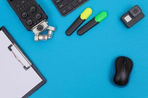 Top View of Photographer's, Videographer's or Blogger's Workplace. Digital Gadgets Lying on Blue Table - Flat Lay photo