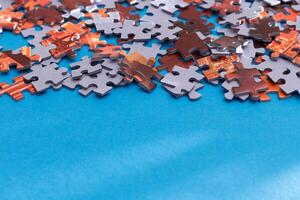 Mixed Pieces of a Colorful Jigsaw Puzzle Lie on the Blue Background With Copy Space - Strategy and Solving Problem Concept photo