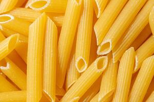 Uncooked Penne Rigate Pasta. A Culinary Canvas of Penne Macaroni, Creating a Lively and Textured Background for Gourmet Cooking. Dry Pasta. Raw Macaroni - Top View, Flat Lay photo
