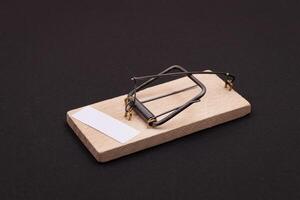 Blank White Sheet of Paper in Wooden Mousetrap - Template. Small Memo Paper in Mouse Trap on Black Background photo